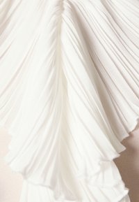 White pleated fabric with layered texture, featuring soft, flowing lines and smooth, lightweight material, creating depth and dimension.