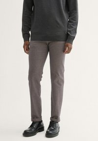 Grijze sweatshirt gecombineerd met lichtgrijze slim-fit broek en zwarte veterschoenen. De broek heeft een subtiele textuur en omgeslagen broekspijpen.