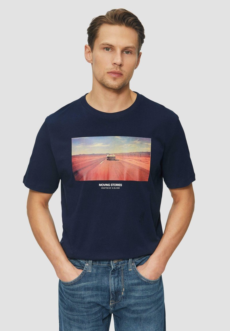 Donker marineblauw T-shirt met korte mouwen, met een centrale afbeelding van een auto op een weg, met de tekst "BEWEGENDE VERHALEN" onder de afbeelding. Katoenen materiaal.