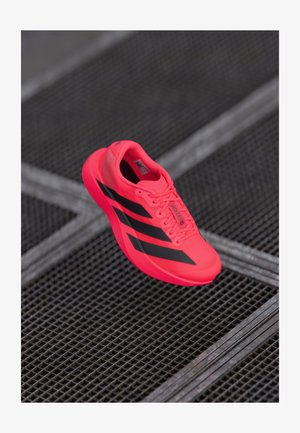Baskets de course rose vif avec des rayures noires, fabriquées en matériau en maille léger, avec une semelle texturée et un design à lacets.