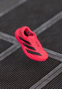 Lys pink Adidas løbesko med sorte striber, letvægtsmateriale, tekstureret overdel, polstret krave og snøresystem for en sikker pasform.