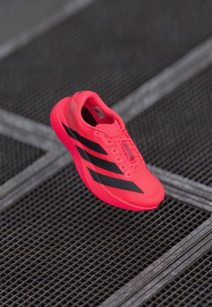 Bright pink Adidas running shoe with black stripes, lightweight material, textured upper, padded collar, and lacing system for secure fit.