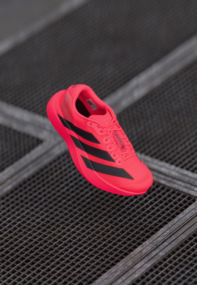 Lys pink Adidas løbesko med sorte striber, letvægtsmateriale, tekstureret overdel, polstret krave og snøresystem for en sikker pasform.