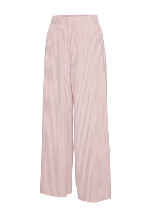 Close-up van een persoon die lichtroze, geribbelde gebreide broek met een elastische tailleband draagt, waarbij een deel van de hand en taille zichtbaar is.