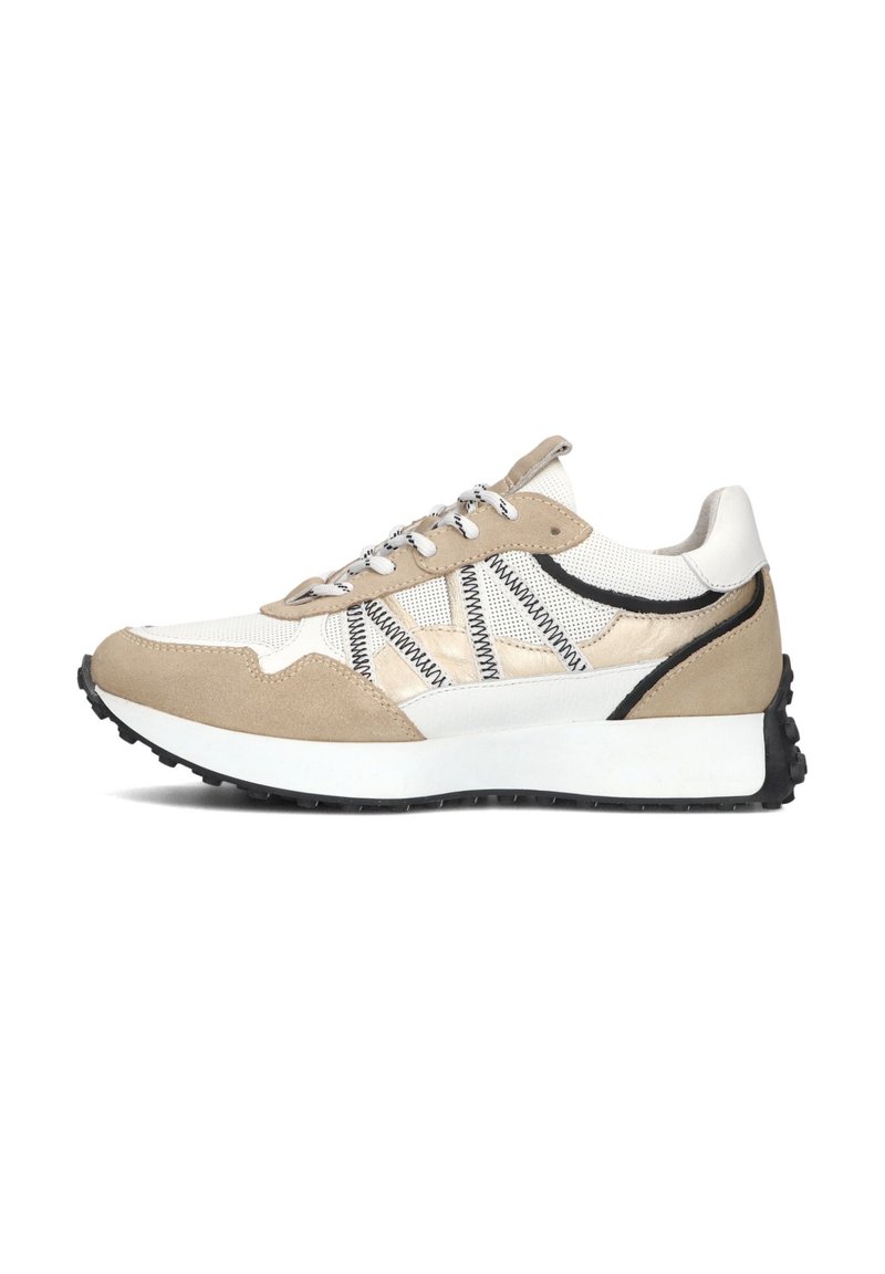 Beige en witte sneaker van suède en mesh materialen. Heeft contrasterende zwarte accenten, een vetersluiting en een dikke zwarte rubberen zool.