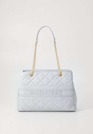 Sac à main matelassé blanc Valentino avec bandoulières chaîne dorée et nom de la marque embossé sur le panneau avant sur un fond clair uni.