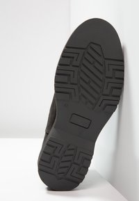 Suola di scarpa in gomma nera con un motivo testurizzato e scanalature pronunciate, dotata di un logo rettangolare e segnato con la taglia 41.