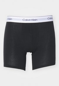 Boxer in cotone nero con elastico in vita recante il logo Calvin Klein in bianco e grigio chiaro. Presenta un design aderente e una texture liscia.