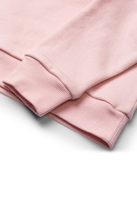 Tessuto di felpa rosa chiaro con polsini a costine; texture liscia; maniche ripiegate che mostrano un design casual e un colore morbido.