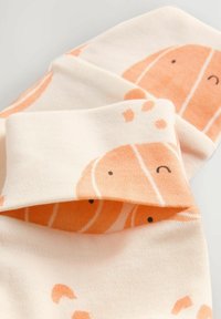 Bomullssockor med krämfärgad bas som har ett lekfullt mönster av lax i orange och svarta detaljer, rullade upptill med en mjuk textur.