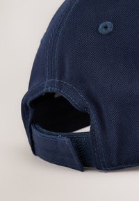 Marinblå basebollkeps med texturerat tyg, justerbar kardborreband och sydda detaljer på visiret och kronan.