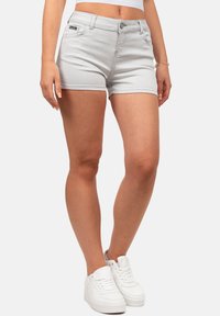 Shorts en denim gris clair avec une coupe ajustée, fermeture à bouton à l'avant et ourlet soigné. Associés à des baskets blanches pour un look décontracté.