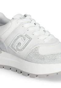 Sneaker bianco con tessuto testurizzato, con strass luccicanti ai lati, suola in gomma spessa e punta arrotondata. Presenta un classico design con lacci.