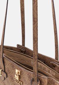 Brązowa syntetyczna torebka o teksturowanej powierzchni, wyposażona w złote okucia, dwa uchwyty i zamykane na zamek komory. Logo widoczne na przodzie.