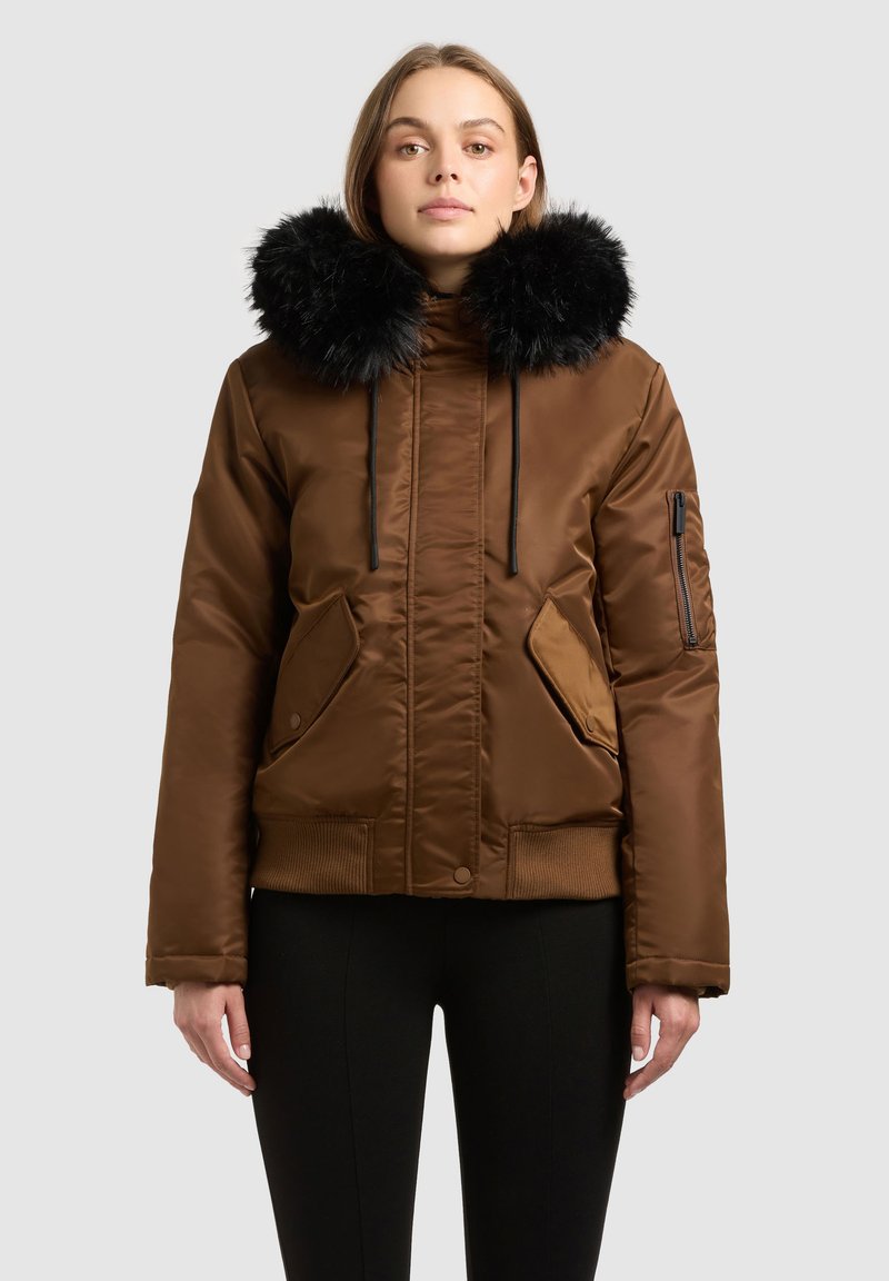 Hnědá péřová bunda s černým umělým kožešinovým límcem, kapsou na zip na rukávu a žebrovaným lemem. Má také šňůrky u límce.