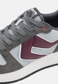 Szürke velúr és hálós sneaker bordó részletekkel, fehér szegéllyel és szürke fűzőkkel; texturált talp a tapadásért és a támogatásért.