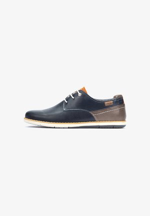 Scarpa in pelle blu con superficie liscia, accenti marroni, suola bianca e dettaglio del tallone arancione. Presenta lacci e cuciture lungo i bordi.