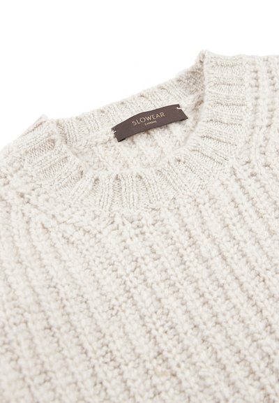 Hellgrauer Strickpullover mit strukturiertem Muster, ausgestattet mit einem gerippten Rundhalsausschnitt und einem braunen Etikett mit der aufgenähten Aufschrift "SLOWEAR".