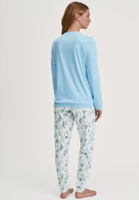 Lichtblauw long-sleeve top gecombineerd met lichtblauwe pyjamabroek met een patroon van verschillende illustraties in donkerblauwe tinten.