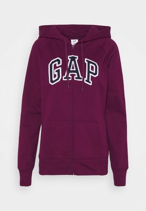 Tummanvioletti vetoketjullinen huppari, jossa on etutaskut, nyörisäädettävä huppu ja suuri valkoisella ääriviivalla varustettu GAP-kirjainrivi rinnassa.