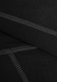Sort tekstil med en glat overflade og teksturerede, diagonale stingdetaljer. Designet viser et close-up af lagdelt stof.