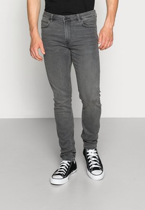 Jeans ajustados grises hechos de denim, con un diseño clásico de cinco bolsillos y cierre de cremallera, combinados con zapatillas altas negras.