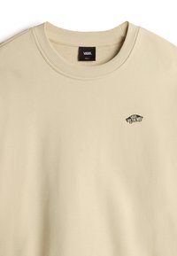 Sudadera beige hecha de suave algodón con un cuello redondo acanalado. Presenta un pequeño logo negro de Vans en el pecho. Textura suave, diseño casual.