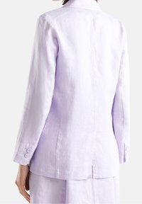 Jasnofioletowa lniana marynarka o dopasowanym kroju, z pojedynczym rozcięciem z tyłu i mankietami zapinanymi na dwa guziki. Prosta, gładka faktura.