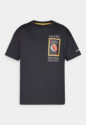T-shirt noir en coton à manches courtes, présentant un graphique coloré de National Geographic et du texte sur le devant, avec des accents jaunes contrastants.