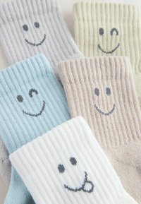 Bunte, gerippte Socken aus weichen Materialien mit Smiley-Motiven. Farben umfassen Blau, Grau, Beige, Weiß und Hellgrün.