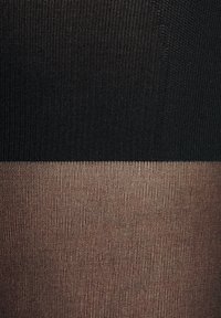 Collant neri a costine nella parte superiore; calze color beige trasparenti nella parte inferiore, con una texture liscia, che mostra un chiaro contrasto di colore.