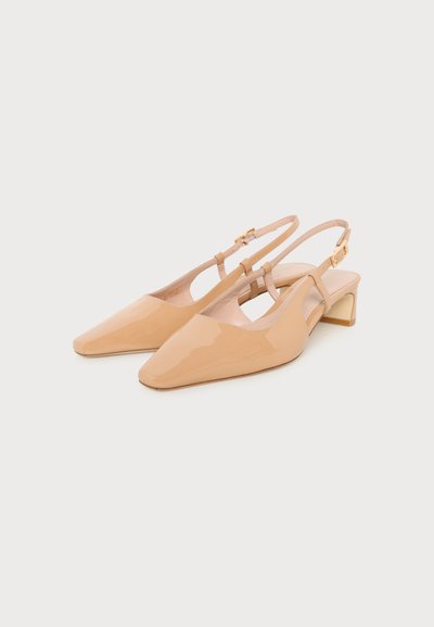 Chaussures slingback en cuir verni beige à bouts pointus, talons bas carrés et brides à boucle dorée sur fond blanc.