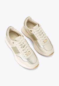 Jasne kremowe sneakersy z metalicznymi złotymi akcentami, panelami z siateczki, płaskimi sznurowadłami i gumową podeszwą. Okrągły czubek i wyściełane wnętrze.