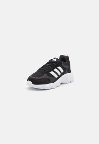 Zapatilla deportiva negra con acentos en blanco, parte superior de malla, cuello acolchado, punta redonda y suela texturizada diseñada para agarre y soporte.