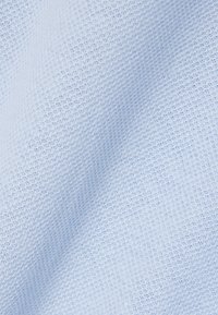 Tissu bleu clair avec un motif tissé finement texturé, présentant des plis doux et des ombres.