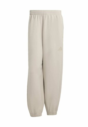 Lys beige sweatpants med elastisk talje, tapered cuffs og et diskret præget logo på venstre lår. Glat stofstruktur.