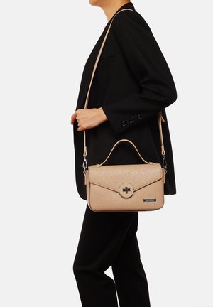 Borsa a tracolla in pelle beige con finitura testurizzata, chiusura magnetica circolare, opzioni di trasporto duali (manico e tracolla) e minimi accenti hardware.