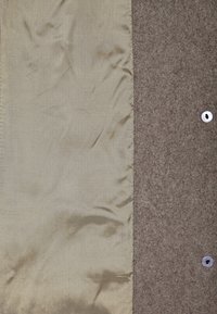 To paneler af stof: det ene glat, lys beige, og det andet struktureret, mørkebrunt, med en sølvtrykknap detalje på højre side.