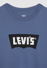 Mėlynas medvilninis marškinėliai su apvaliu kaklu, su dideliu juodu ir baltu "LEVI's" logotipu priekyje, pagaminti iš lygaus audinio.