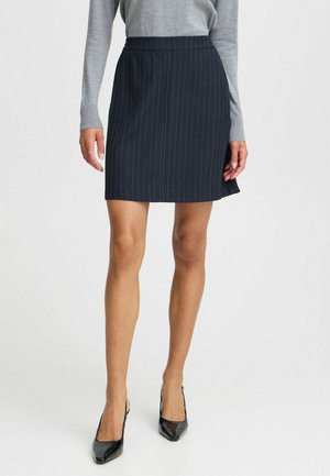 Navy pinstripe skirt with a fitted waist, straight cut, and a smooth texture, paired with black glossy high-heeled shoes.