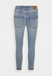 Jeans skinny azul claro feitos de denim, com uma cintura média, dois bolsos traseiros e um retângulo de couro castanho da marca na parte de trás.