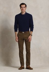 Pulover din lână tricotat cu model, asortat cu o cămașă cu imprimeu, chinos bej și pantofi maro. Croială slim și paletă de culori neutre.
