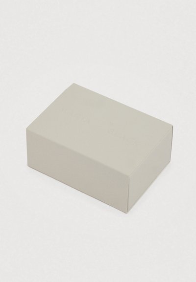 Szögletes világosszürke doboz masszív kartonból, matt felülettel és a tetején dombornyomott "MARIA BLACK" felirattal.