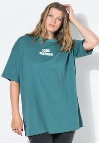Světlomodré oversized tričko vyrobené z měkké bavlny, s potiskem "ICED MATCHA" v tučném bílém písmu na přední straně. Krátké rukávy a volný střih.