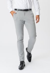 Grå strækbukser har et tapered design, sidelommer og en glat overflade, kombineret med sorte læderdress shoes.