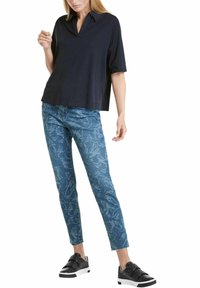 Námořnický top s krátkým rukávem a límečkem, zkombinovaný s modrými džínami se květinovým vzorem a černými teniskami s bílou podrážkou.