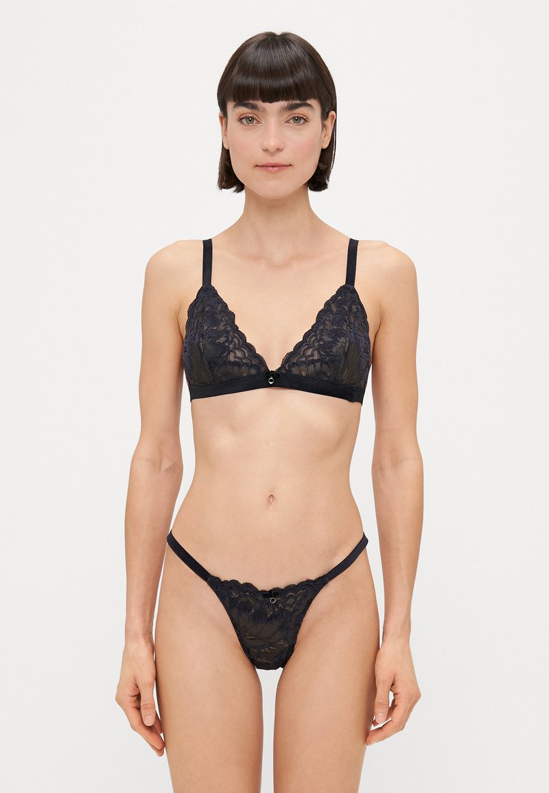 Schwarzer Spitzen-Dreiecks-Bralette mit verstellbaren Trägern, mit gewelltem Rand und einem kleinen Frontverschluss. Passender Spitzen-String mit dünnen Seiten.