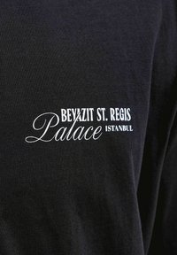 Zwarte stof met witte tekst "BEYAZIT ST. REGIS Palace ISTANBUL" in een mix van schreef- en schreefloze lettertypen.