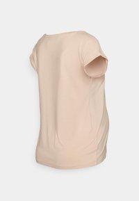 T-shirt pêssego de mangas curtas, feito de um tecido macio. Gola redonda, corte relaxado e detalhes ligeiramente franzidos nas costuras laterais.