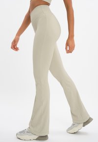 Beige geribbelde flared legging met een hoge tailleband, voorzien van een subtiele logo-detail en een gladde, rekbare textuur.
